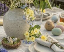 Tisch mit Osterdekoration und Sträuchern in Vase, Ostreier auf dem Tisch und Tellern mit Besteck