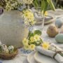 Tisch mit Osterdekoration und Sträuchern in Vase, Ostreier auf dem Tisch und Tellern mit Besteck